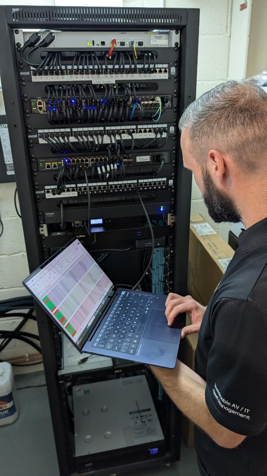 man working on a laptop in front of a server